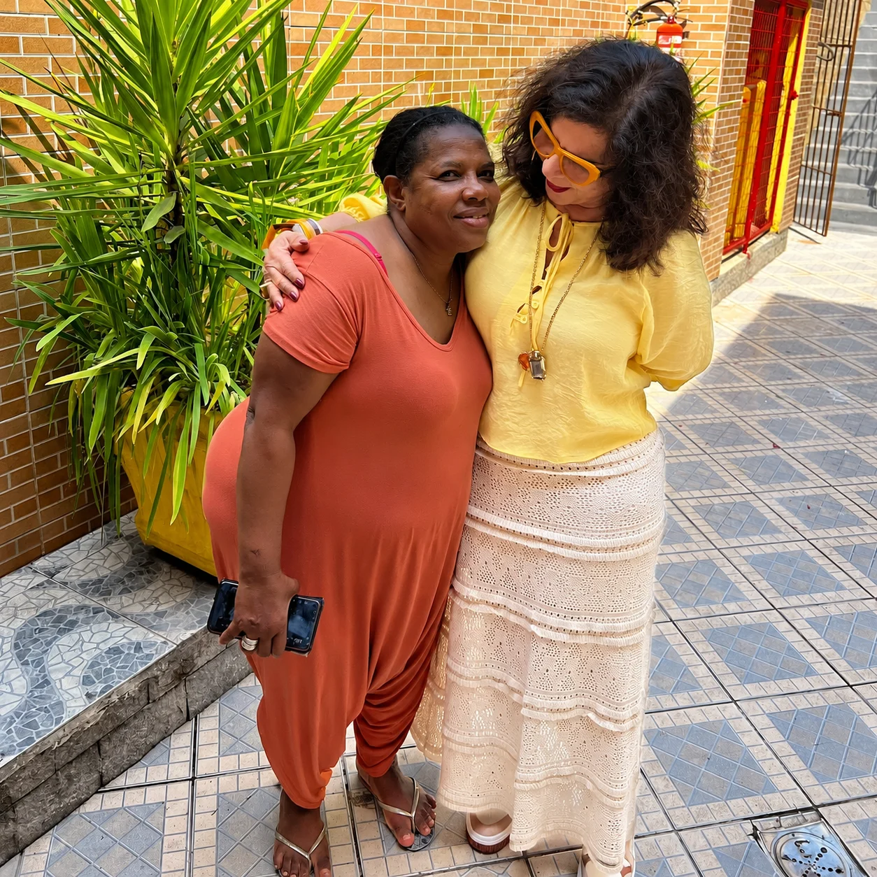 Duas mulheres compartilham um abraço no pátio da Associação Irmãos da Solidariedade.